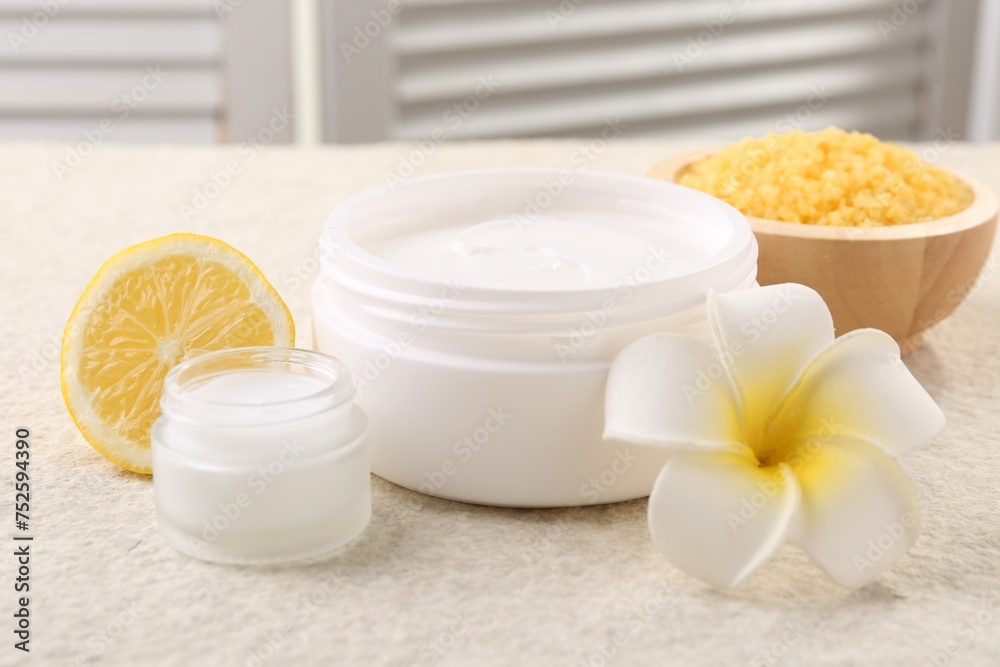 Composition with body care cream in open jars on light textured table, closeup
