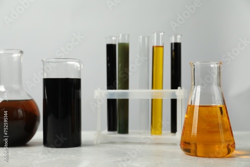 Laboratory glassware with different types of oil on white table photo