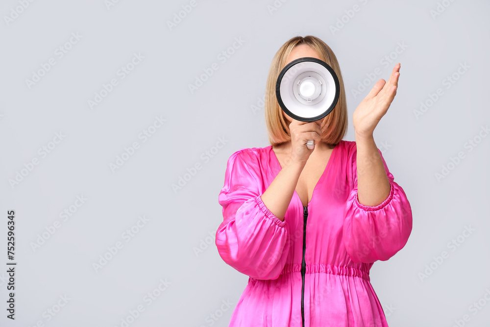 Fototapeta premium Mature woman with megaphone on grey background