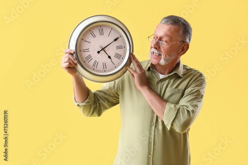 Mature man with clock on ye...