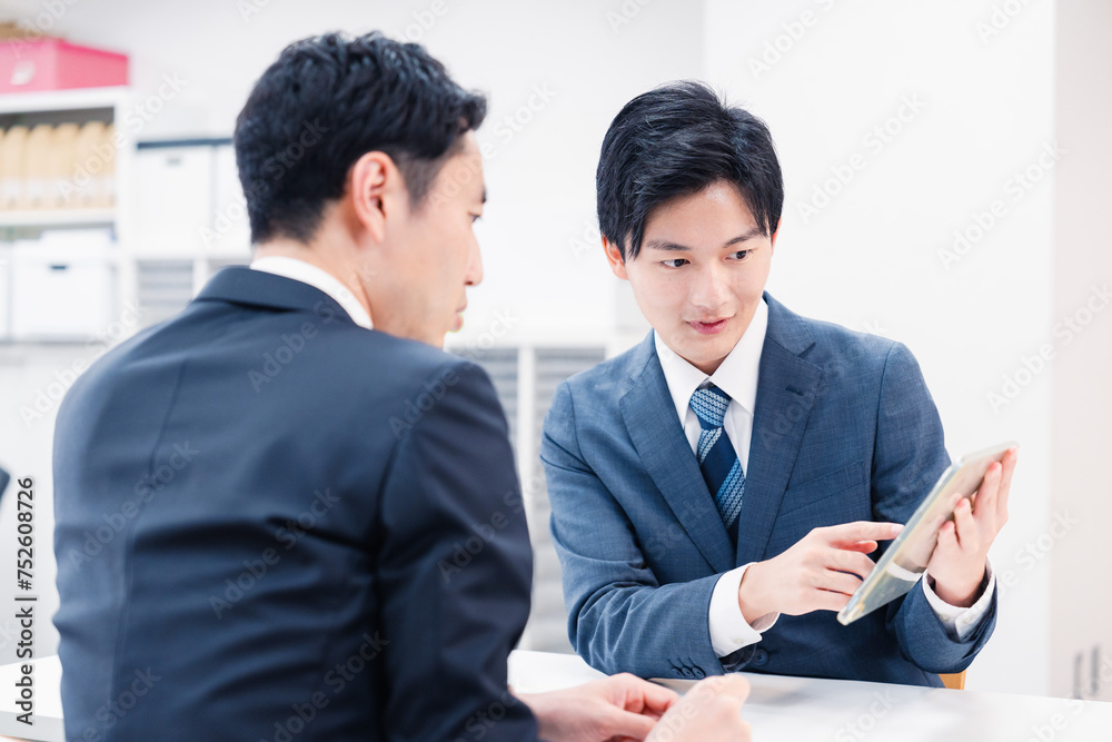 タブレット端末を使い窓口で説明をするビジネスマン