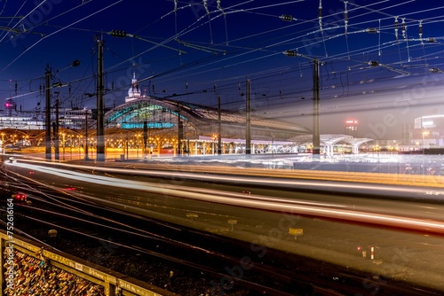 An illuminated railway station at night with light trails of trains created by long exposure, Cologne Central Station at night photo