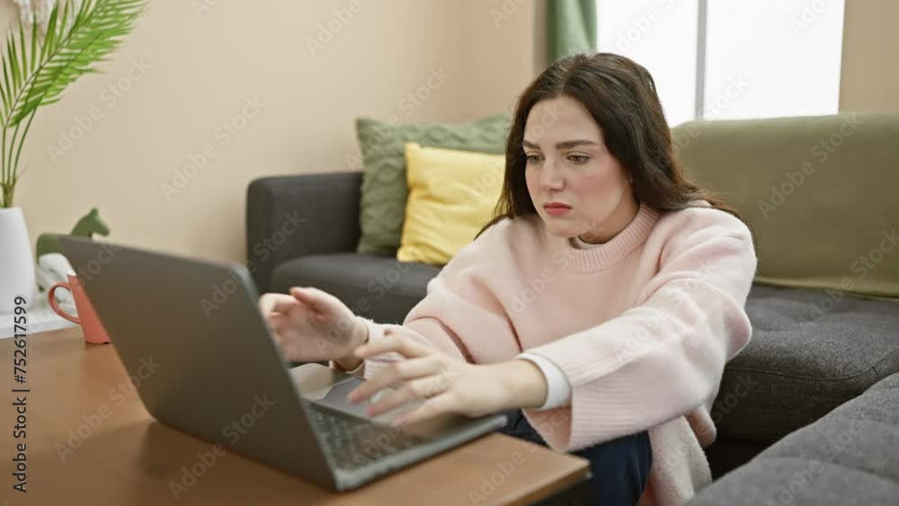 Young caucasian woman using a laptop on a couch in a cozy living room, looking focused and then stressed Young caucasian woman using a laptop on a couch in a cozy living room, looking focused and then stressed