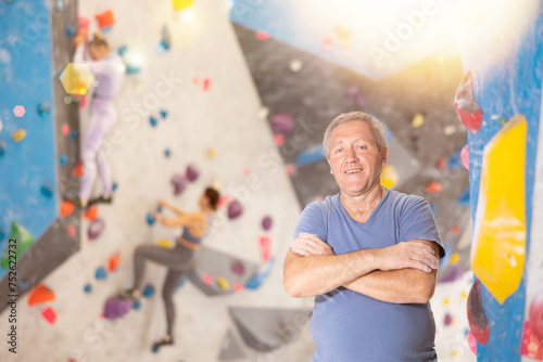 Adult strong man in sportswear posing on climbing wall