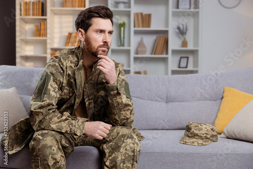 Man in uniform, returning home, battling depression. He is sitting on couch and looking away