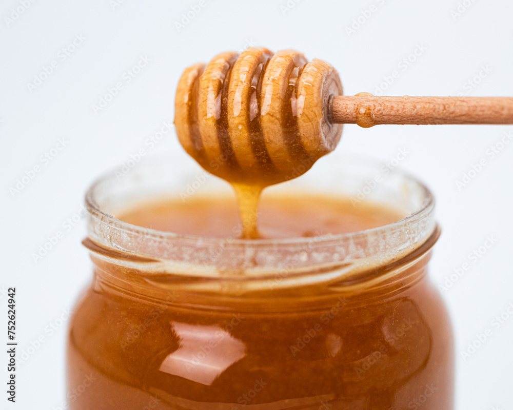 Honey in a glass jar with a special wooden spoon Honey in a glass jar with a special wooden spoon