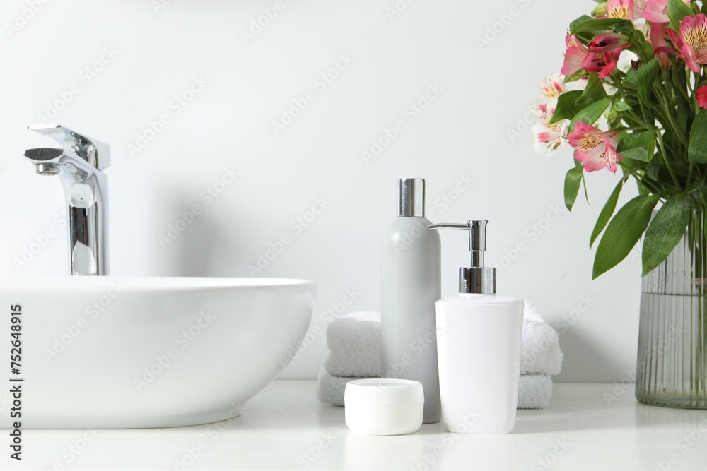 Vase with beautiful Alstroemeria flowers and toiletries near sink in bathroom - obrazy, fototapety, plakaty 