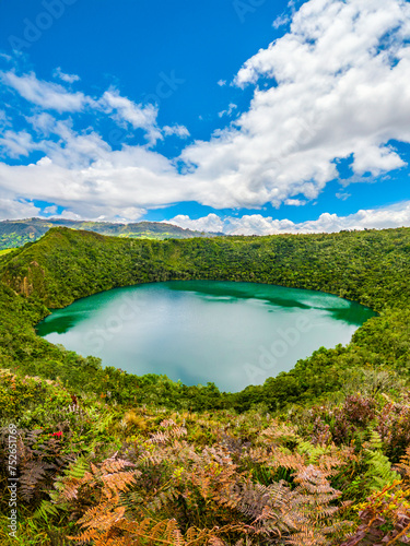 Breathtaking view of Guatavita Lagoon, Cundinamarca, surrounded by lush greenery under a vibrant sky