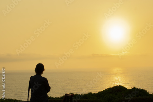 silhouette of lady standing looking at the horizon on the beach
