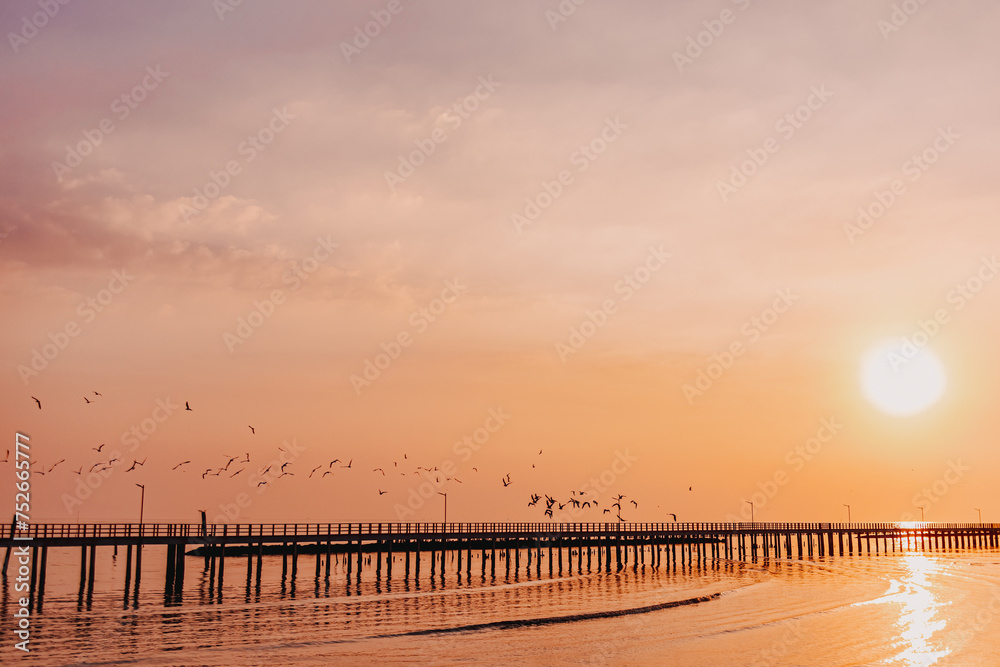Sunset sea view seascape orange clear sky with long bridge.