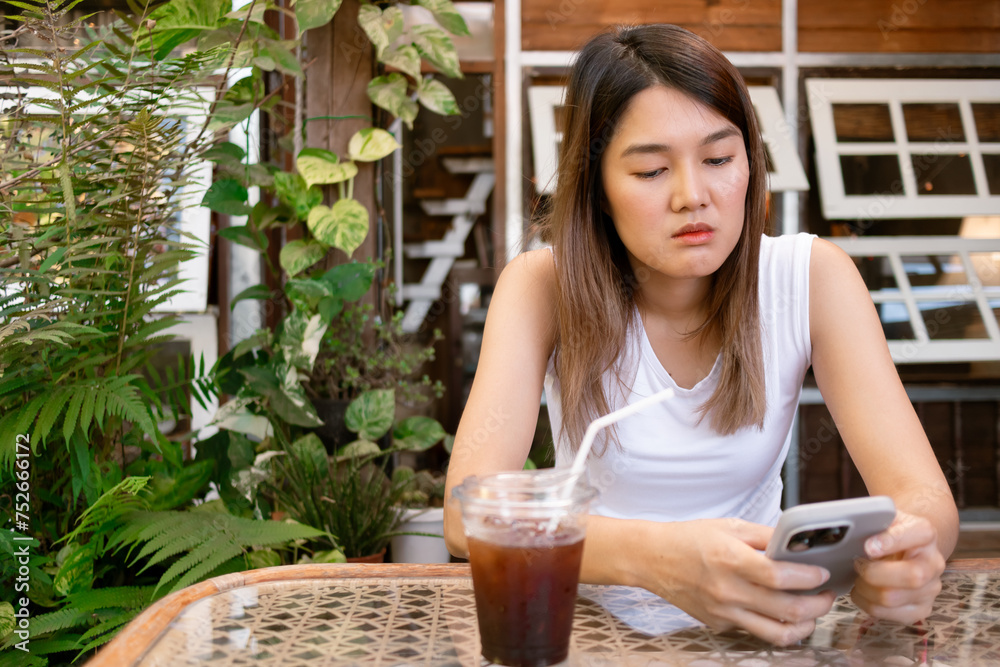 Asian woman browsing social media in mobile, feeling sad and depress.