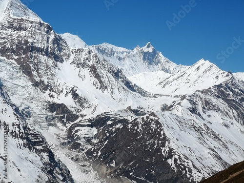 A majestic mountain range glistens with pure white snow beneath a serene blue sky