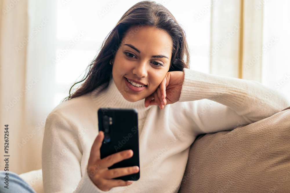 Connected at Home: Young Woman Sitting on Sofa Using Smartphone Connected at Home: Young Woman Sitting on Sofa Using Smartphone