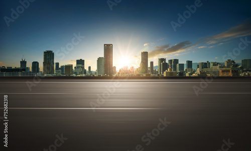 Fototapeta Naklejka Na Ścianę i Meble -  Motion blurred asphalt empty road side with city skyline background. Sunrise.
