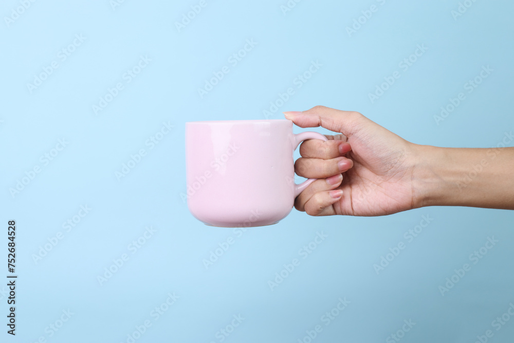 Obraz premium Hands Holding Ceramic Mug Isolated on Blue Background