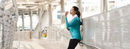 Fotografie Asian sporty woman drinking water to rehydrate after jogging exercise