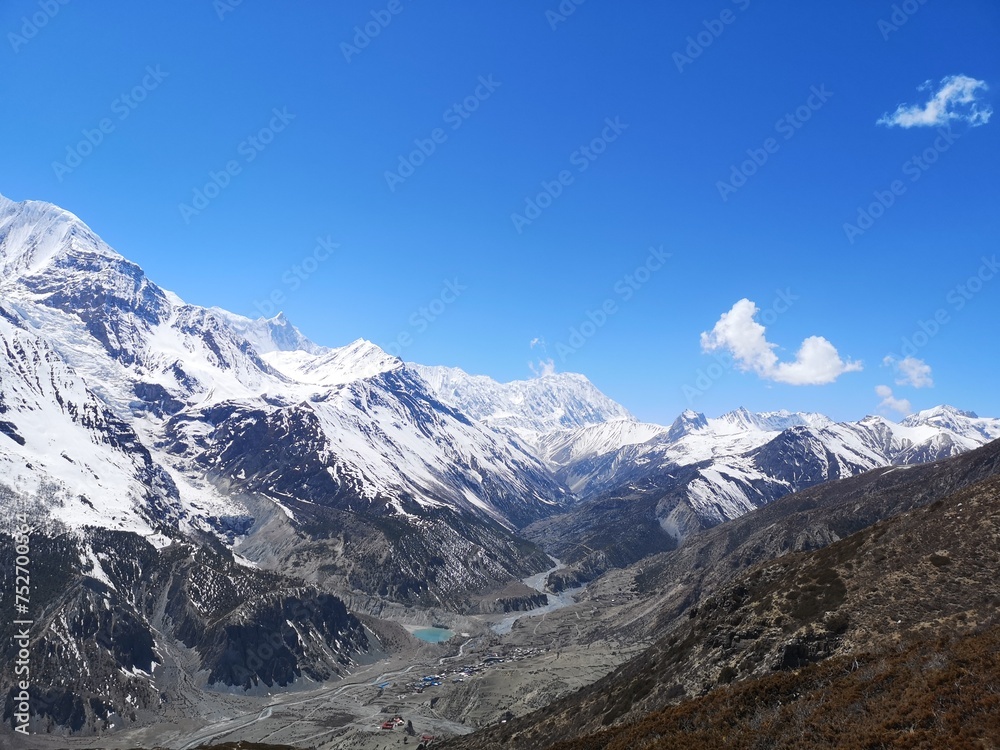 Majestic snowy mountains rise high against the blue sky