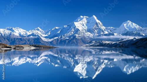 Snow-covered peaks reflecting in a serene lake, creating a breathtaking panorama under a clear, deep blue sky. © Hasni