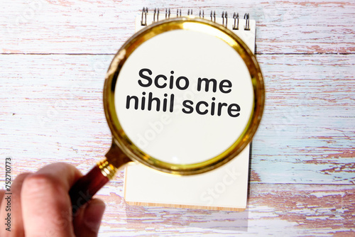 Scio me nihil scire It is translated from Latin as I know I don't know anything. through a magnifying glass on a notebook photo