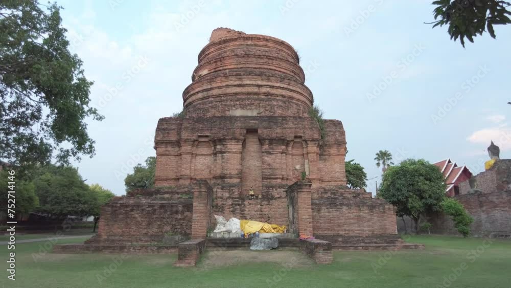 Ancient brick stupa under clear sky with draped yellow cloth and Buddha statue remnants at a serene temple in Ayutthaya,Thailand. Ancient brick stupa under clear sky with draped yellow cloth and Buddha statue remnants at a serene temple in Ayutthaya,Thailand.