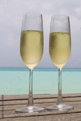 A vertical closeup of two champagne glasses against the beautiful turquoise sea The Maldives 