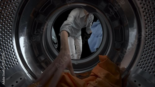 View from inside a washing machine of a housewife woman filling the drum with colored clothes. Green screen, isolated on black background with alpha channel.