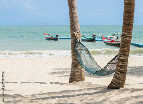 Hammock under coconut palm trees at sandy beach on sunny day, travel summer holidays concept