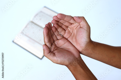 Close-up of hands opening up palms in prayer after reciting the Quran during Ramadan on a white background photo