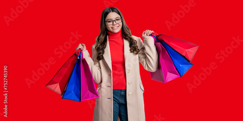 Girl shopping. Teen girl update wardrobe. Shopping sale and discount. Girl shopper with purchase isolated on red. Girl shopaholic hold shopping bag. Black Friday sale