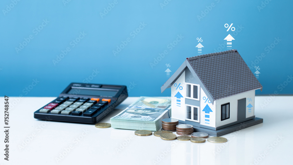 Interest rate and dividend concept. The model house with percentage symbol and up arrow for increasing interest rates, stacks of coins and calculator. home loan, mortgage, house tax. asset management. Interest rate and dividend concept. The model house with percentage symbol and up arrow for increasing interest rates, stacks of coins and calculator. home loan, mortgage, house tax. asset management.