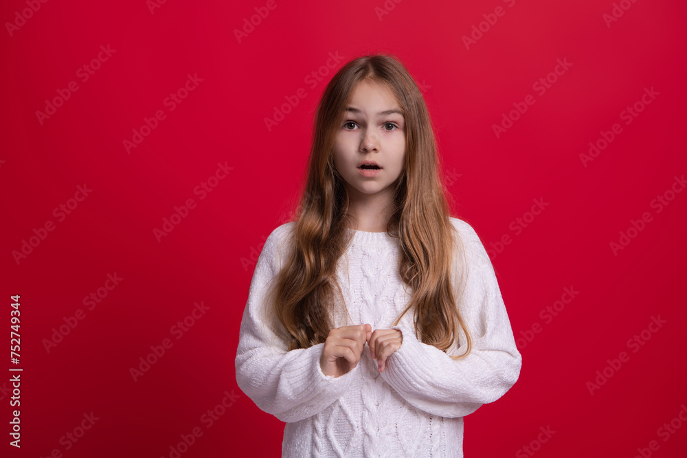 Trendy fashion outfit in winter. Winter amazed girl child. Style portrait of teen girl in warm clothing and winter sweater isolated on red. Knitted sweater fashion Trendy fashion outfit in winter. Winter amazed girl child. Style portrait of teen girl in warm clothing and winter sweater isolated on red. Knitted sweater fashion