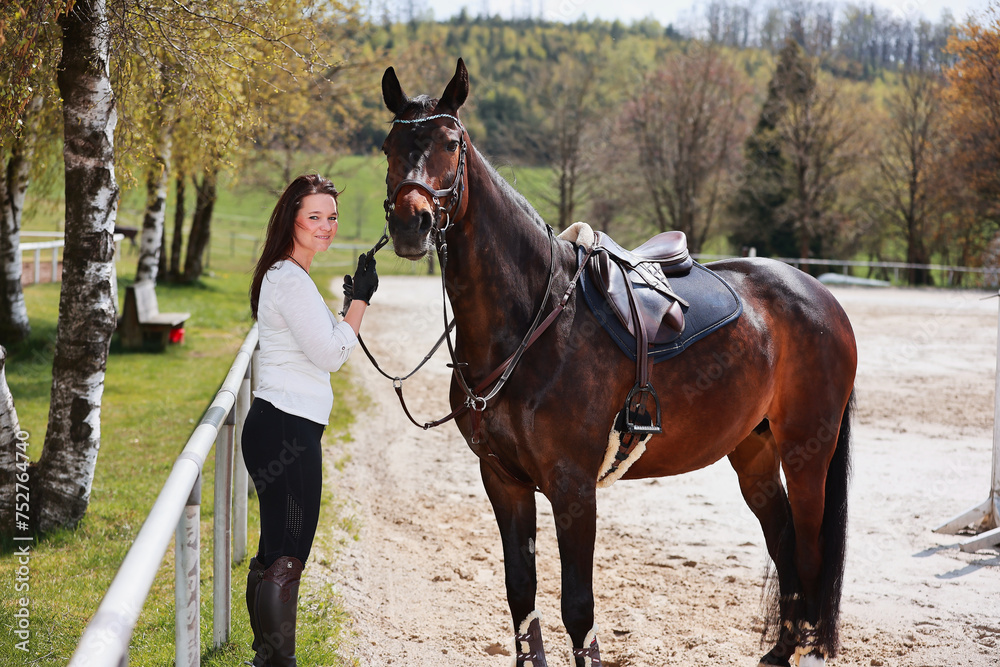 Young Frtau rider with brown long hair in portrait with her horse on the riding arena. Young Frtau rider with brown long hair in portrait with her horse on the riding arena.