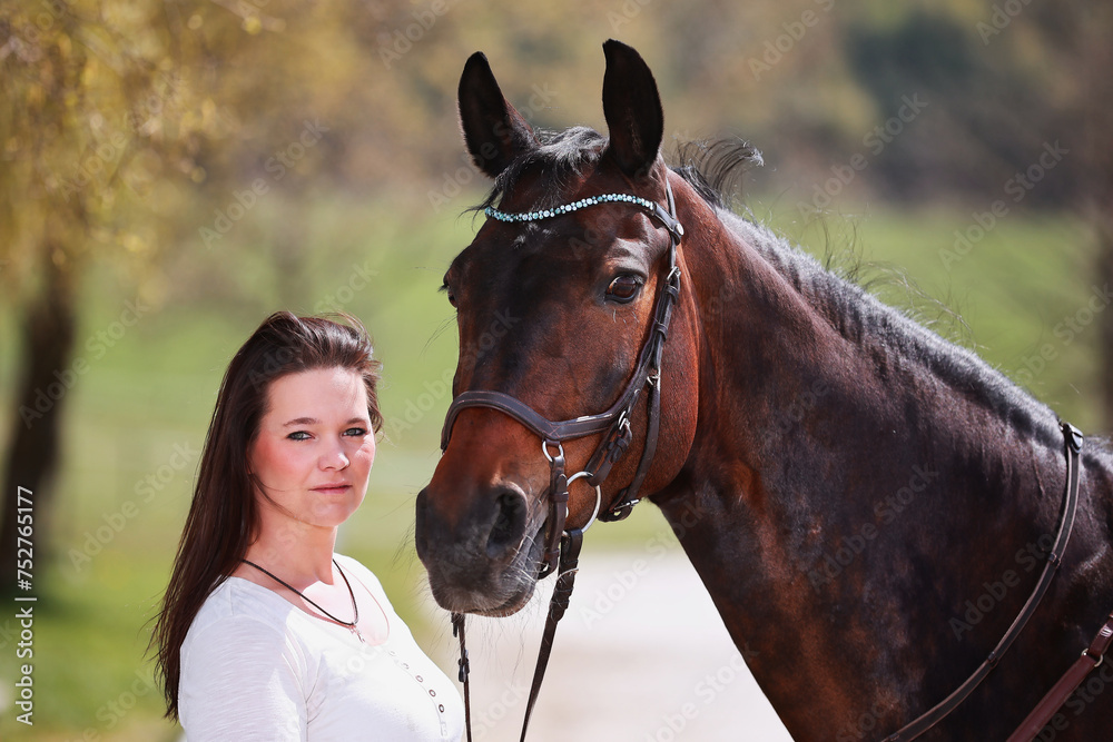 Obraz premium Young Frtau rider with brown long hair in portrait with her horse on the riding arena.