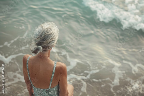 Mujer de 50 años en la playa, mujer mayor de espalda en la orilla del mar photo