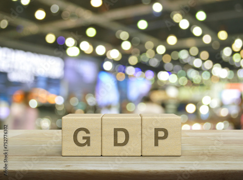 GDP letter on wood block cubes on wooden table over blur light and shadow of shopping mall, Gross domestic product concept © grapestock