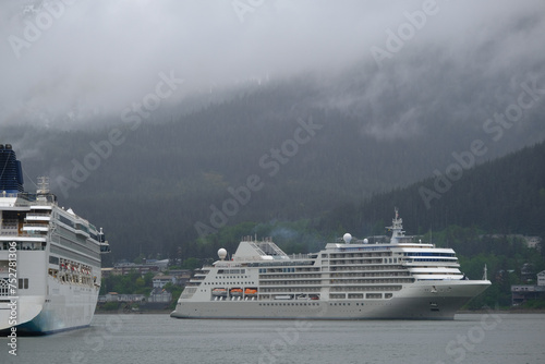 Super deluxe luxury cruiseship cruise ship liner yacht Muse arrival in Juneau, Alaska with panoramic nature scenic coast views on grey misty foggy day