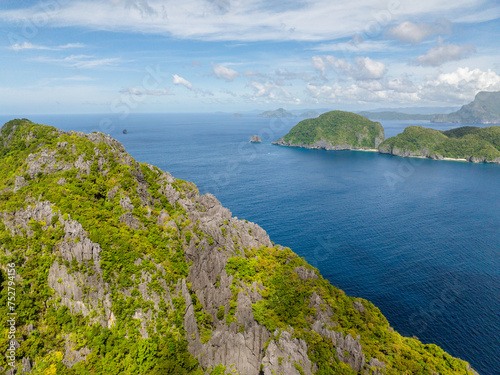 Aerial view of Inambuyod Island from Matinloc. Blue sea, blue sky and clouds. El Nido, Philippines.