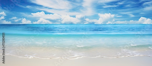 Serenity on the Coast: Tranquil Beach Scene Under a Clear Blue Sky with Fluffy White Clouds