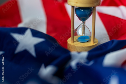 Hourglass and USA flag, soft focus, copy space photo