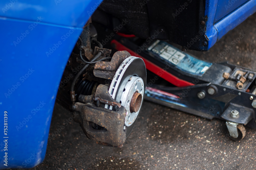 A wheel is removed from a blue car