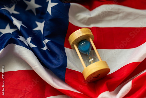 Hourglass and USA flag, soft focus, copy space photo