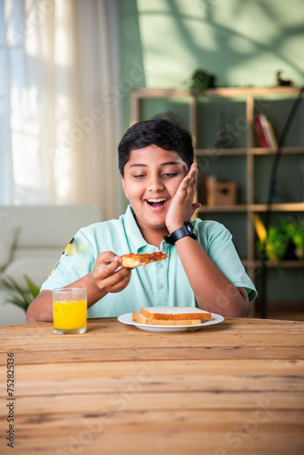 Cute little Indian boy eating pizza at home