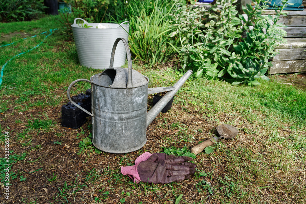 Garden planting. Empty pots, gloves and a trowel lie on the lawn.
