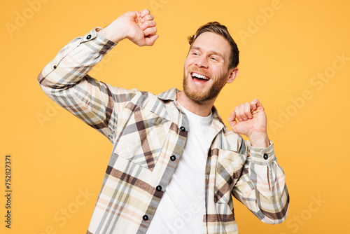 Photos Young smiling happy satisfied positive Caucasian man he wear brown shirt casual clothes raise up hands dance look aside isolated on plain yellow orange background studio portrait