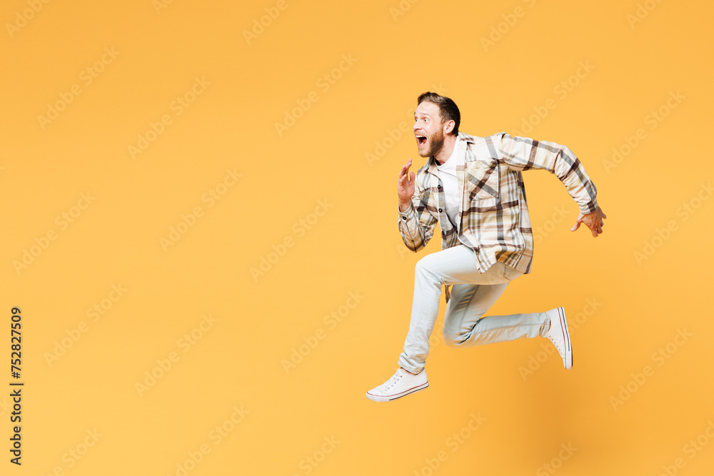 Full body side profile view young Caucasian overjoyed man he wear brown shirt casual clothes jump high run fast hurry up isolated on plain yellow orange background studio portrait. Lifestyle concept. Full body side profile view young Caucasian overjoyed man he wear brown shirt casual clothes jump high run fast hurry up isolated on plain yellow orange background studio portrait. Lifestyle concept.