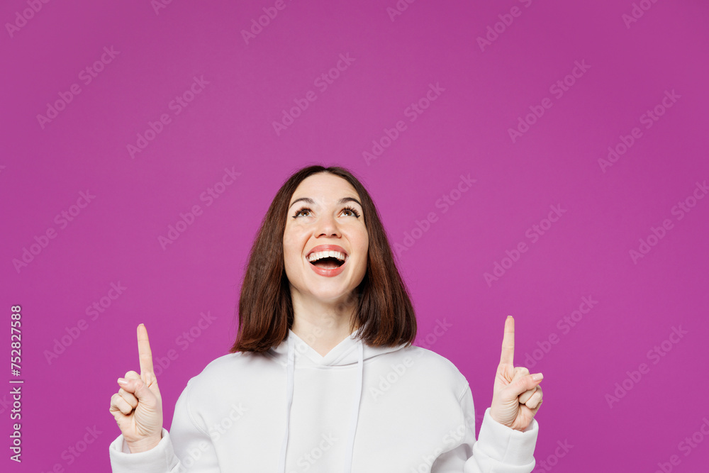 Young shocked happy Caucasian woman wear light hoody casual clothes point index finger overhead indicate on area mockup isolated on plain purple color background studio portrait. Lifestyle concept. Young shocked happy Caucasian woman wear light hoody casual clothes point index finger overhead indicate on area mockup isolated on plain purple color background studio portrait. Lifestyle concept.