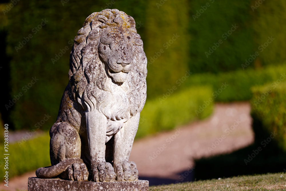 Sitting lion stone statue in a park. Sitting lion stone statue in a park.