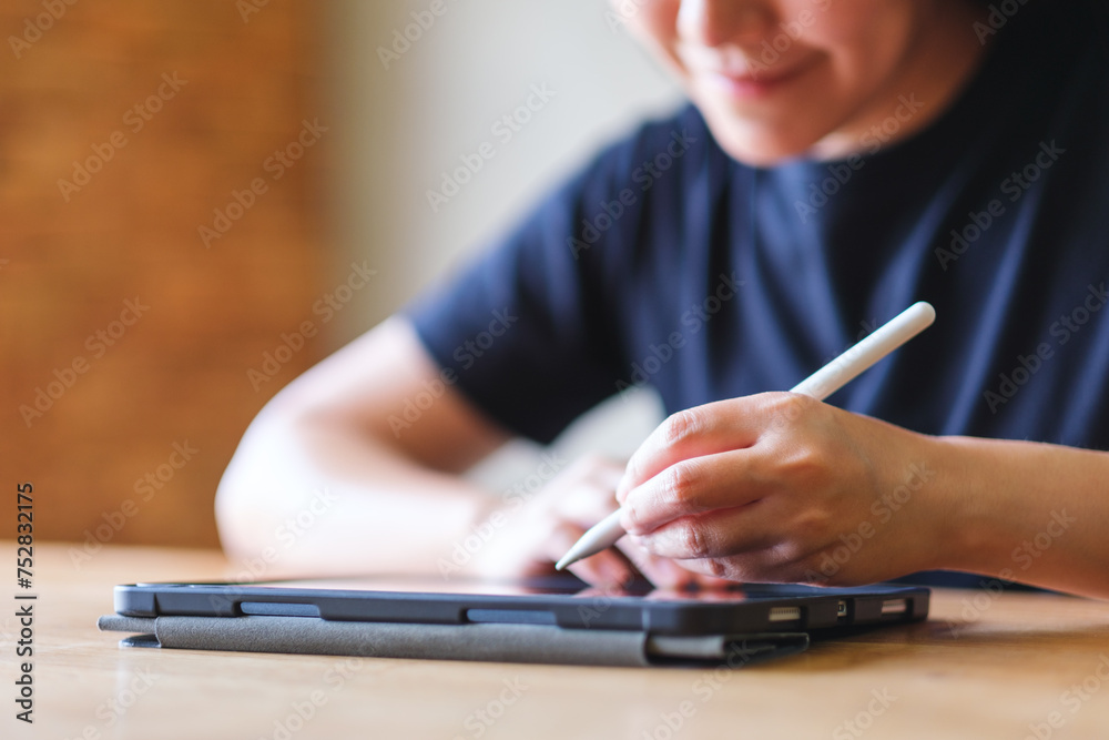 Fototapeta premium Closeup of a young woman using stylus pen technology for working and writing on digital tablet screen