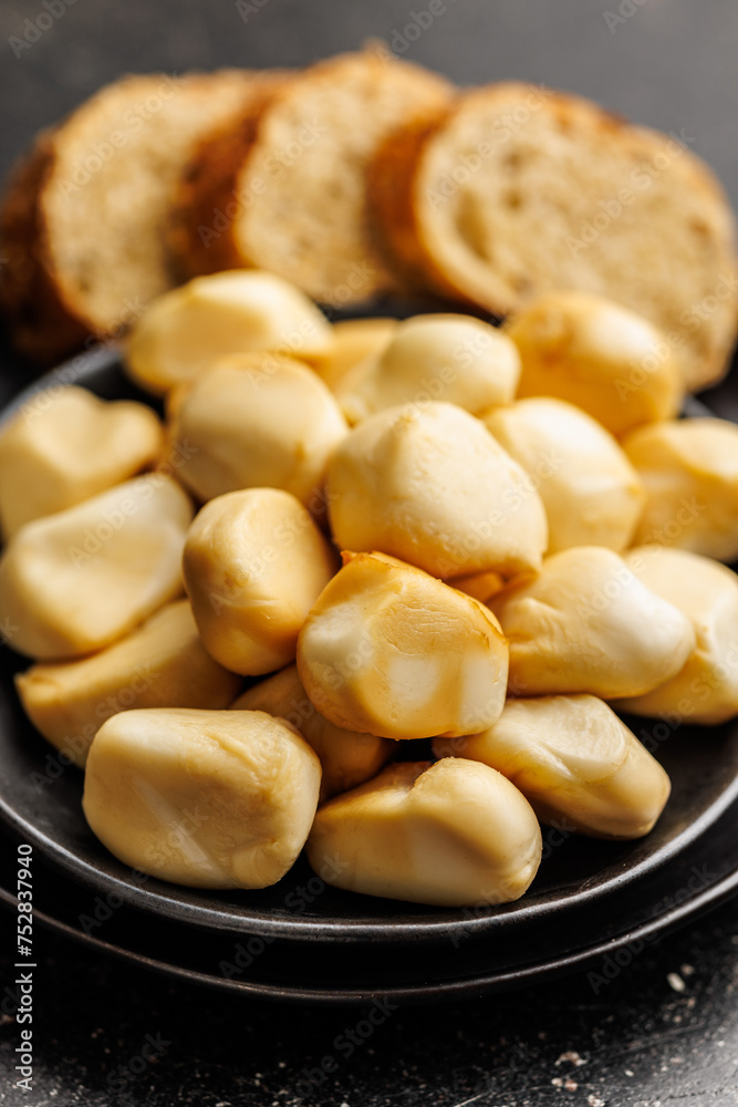 Smoked mini scamorza cheese. Traditional italian cheese on plate on black table. Smoked mini scamorza cheese. Traditional italian cheese on plate on black table.
