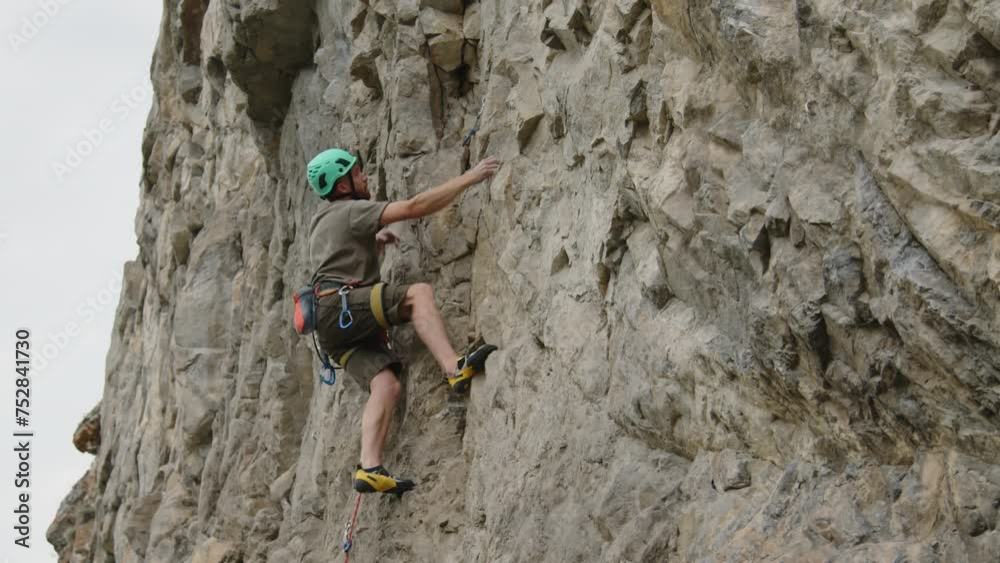 Vidéo Stock Alpinist in helmet and safety harness climbing up steep